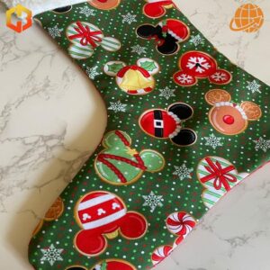 Close-up of Disney Mickey Mouse Cookies Christmas Stocking pattern featuring colorful Mickey-shaped ornaments on green fabric.