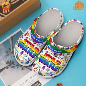 A pair of Star Wars Crocs with rainbow and transgender flag Jibbitz charms attached.