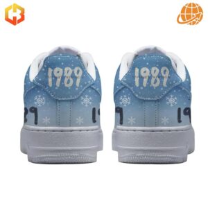 Back view of Taylor Swift 1989 Nike Air Force Shoes with "1989" text and "Taylor's Version" phrase on gradient blue background with white snowflakes.